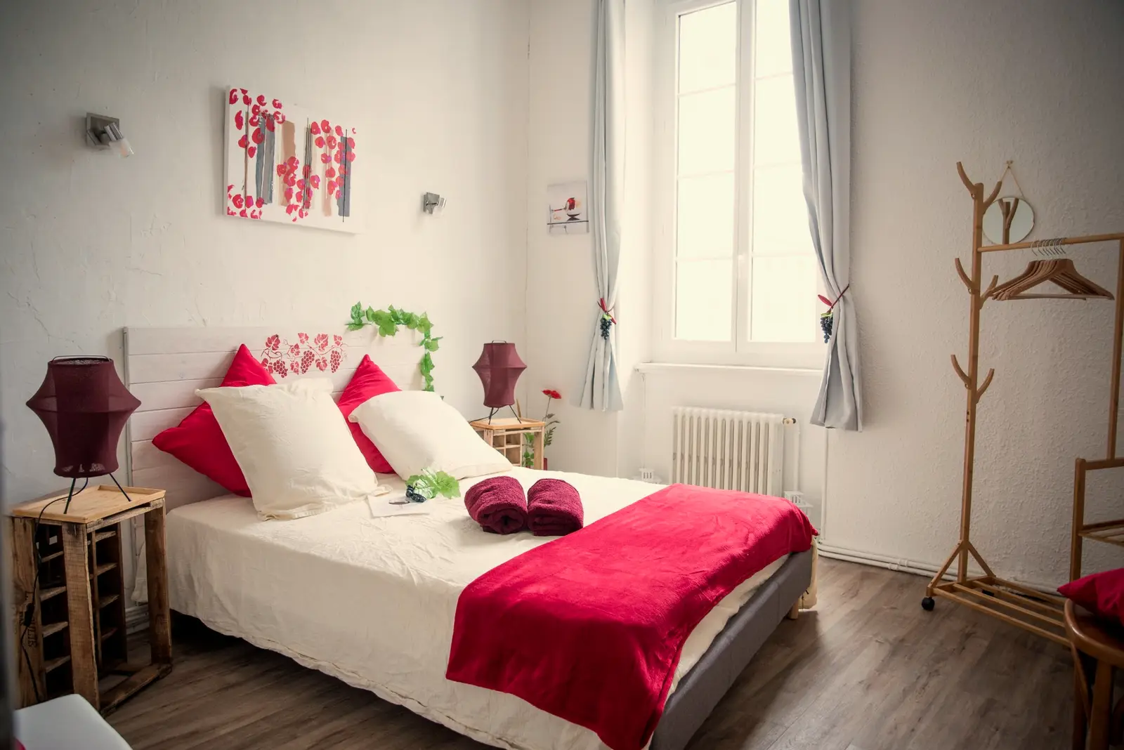 Chambre Vin rouge : lit double, coussins et plaid rouges, tête de lit peinte de vignes